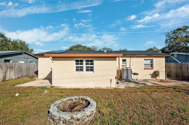 back of property featuring an outdoor fire pit, central AC, a lawn, and a patio