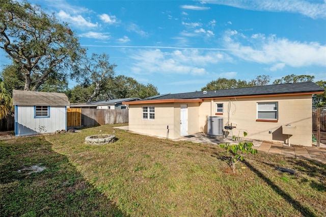 back of house with an outdoor fire pit, a shed, central AC unit, a patio area, and a yard