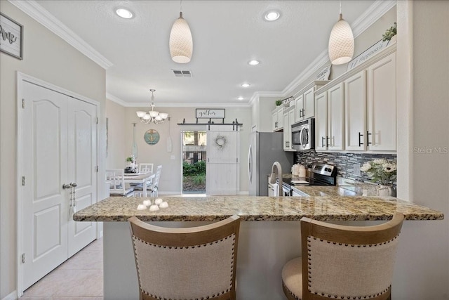 kitchen with hanging light fixtures, appliances with stainless steel finishes, tasteful backsplash, kitchen peninsula, and a breakfast bar area