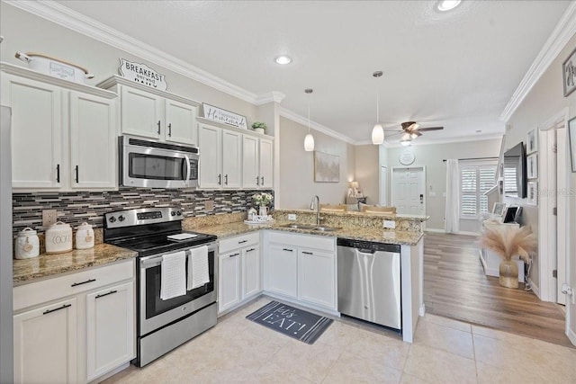 kitchen with kitchen peninsula, stainless steel appliances, sink, pendant lighting, and white cabinetry