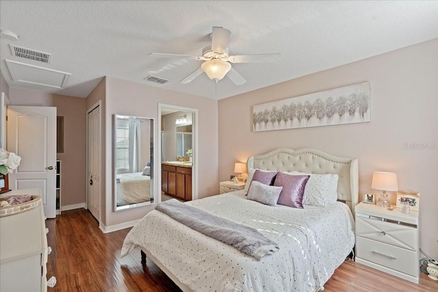 bedroom with sink, ensuite bath, hardwood / wood-style flooring, ceiling fan, and a textured ceiling