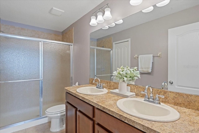 bathroom with tile patterned flooring, vanity, an enclosed shower, and toilet