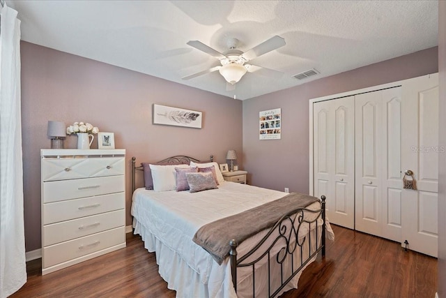 bedroom with ceiling fan, dark hardwood / wood-style flooring, a textured ceiling, and a closet