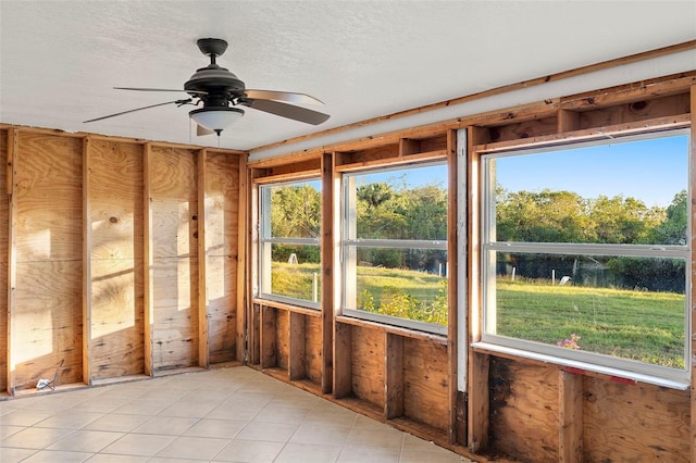 unfurnished sunroom featuring ceiling fan and a healthy amount of sunlight