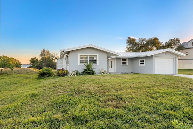 ranch-style house featuring a garage and a yard