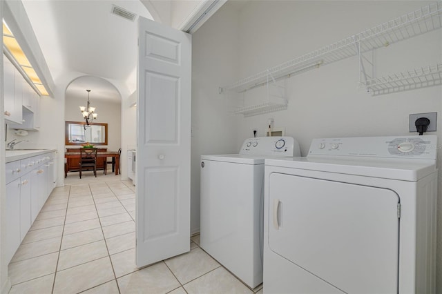 laundry room featuring light tile patterned flooring, sink, washing machine and clothes dryer, and an inviting chandelier