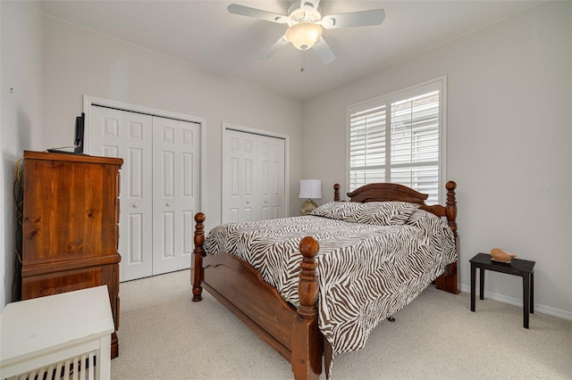 carpeted bedroom with ceiling fan and two closets