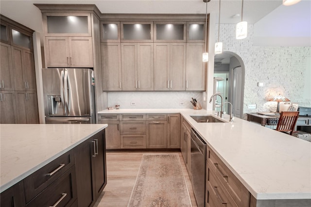 12113 Marblehead Dr, Tampa, FL 33626 - kitchen with appliances with stainless steel finishes, a sink, arched walkways, a peninsula, and light wood finished floors