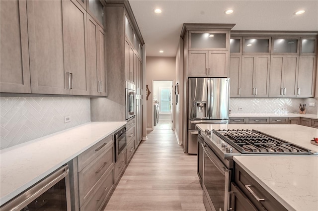 12113 Marblehead Dr, Tampa, FL 33626 - kitchen featuring appliances with stainless steel finishes, beverage cooler, recessed lighting, light wood-style flooring, and light stone countertops