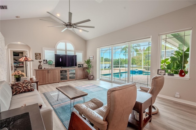12113 Marblehead Dr, Tampa, FL 33626 - living room with a ceiling fan, light wood finished floors, high vaulted ceiling, arched walkways, and baseboards