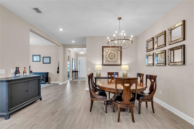 dining area with light hardwood / wood-style flooring and a notable chandelier