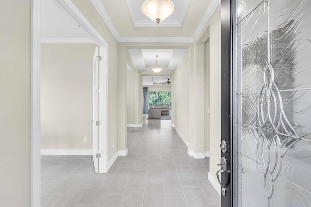 tiled foyer featuring a raised ceiling and crown molding