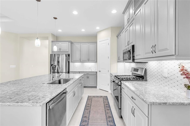 kitchen with a kitchen island with sink, sink, hanging light fixtures, tasteful backsplash, and stainless steel appliances