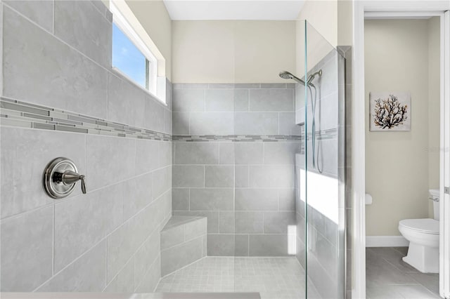 bathroom with tiled shower, tile patterned flooring, and toilet