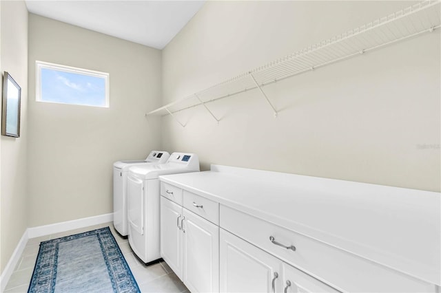 laundry area with washer and dryer, light tile patterned floors, and cabinets