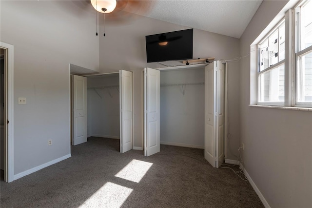 unfurnished bedroom featuring carpet flooring, vaulted ceiling, and two closets