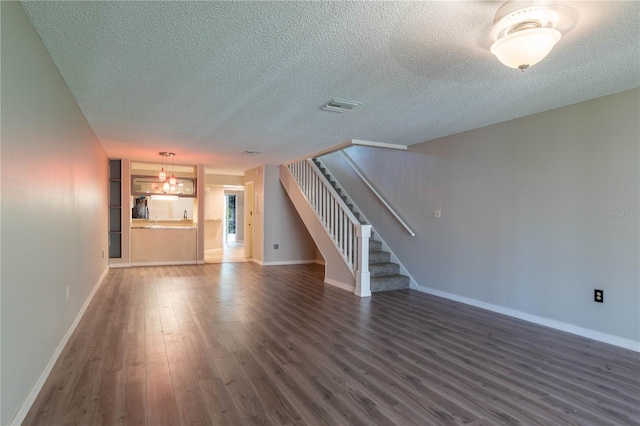 unfurnished living room with a textured ceiling and dark hardwood / wood-style floors