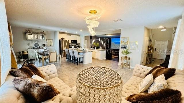 tiled living room featuring a textured ceiling and a chandelier