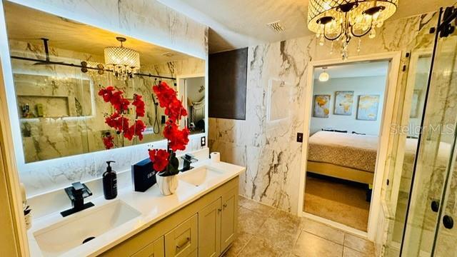 bathroom with a notable chandelier, an enclosed shower, and vanity