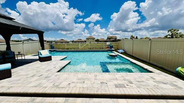 view of swimming pool with a patio area and a jacuzzi