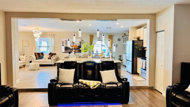 living room featuring a textured ceiling, light hardwood / wood-style flooring, and plenty of natural light