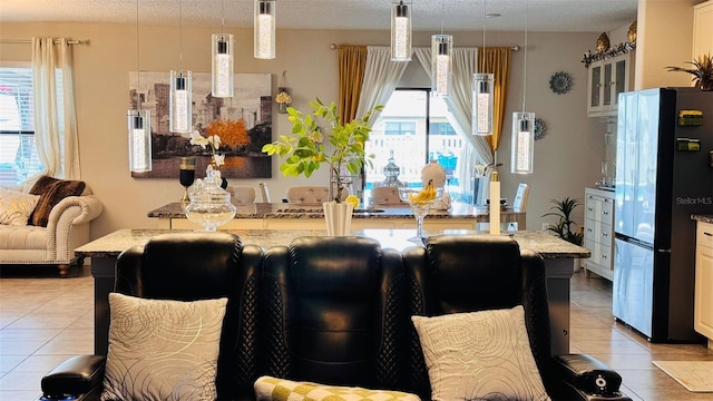 kitchen featuring decorative light fixtures, light stone countertops, white cabinetry, and stainless steel refrigerator