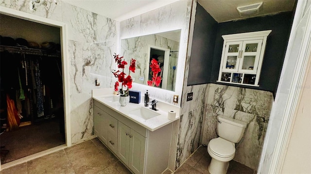 bathroom with vanity, toilet, and tile walls