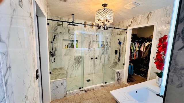 bathroom with tile patterned flooring, a shower with shower door, a textured ceiling, and a notable chandelier