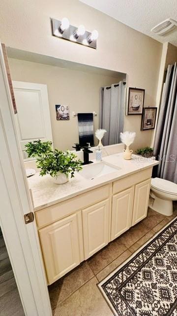 bathroom featuring toilet, a textured ceiling, vanity, and tile patterned floors