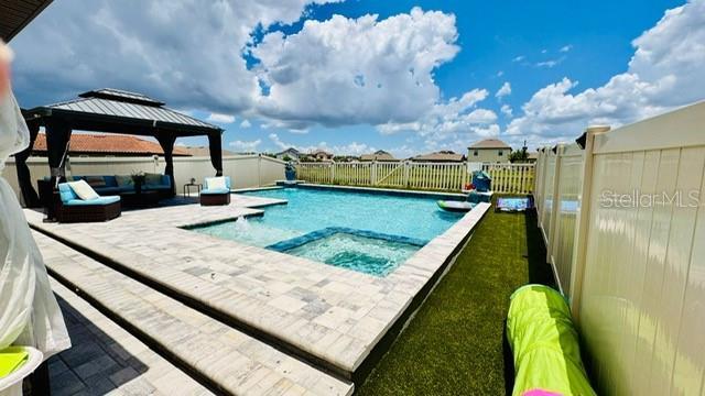 view of swimming pool featuring a gazebo, an outdoor living space, an in ground hot tub, and a patio