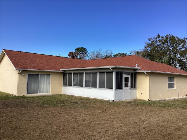 rear view of house featuring a lawn and a sunroom