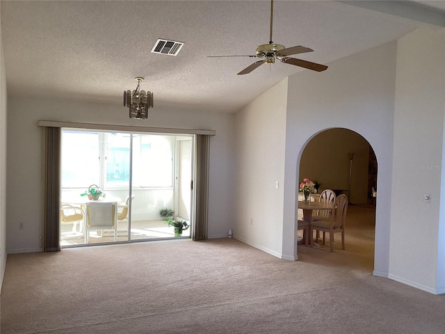 carpeted spare room with ceiling fan with notable chandelier, lofted ceiling, and a textured ceiling