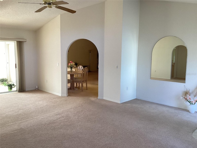 carpeted empty room featuring ceiling fan, a textured ceiling, and vaulted ceiling