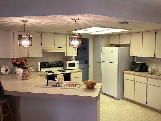 kitchen featuring washer / dryer, white appliances, hanging light fixtures, and a chandelier