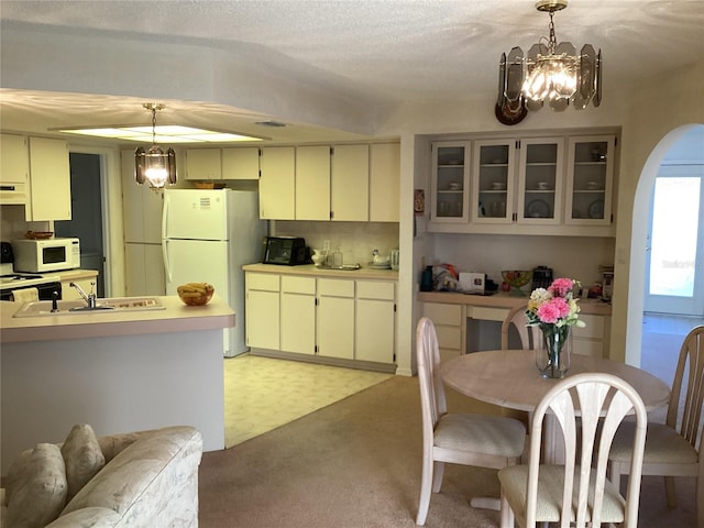 kitchen featuring white appliances, sink, decorative light fixtures, a notable chandelier, and cream cabinetry