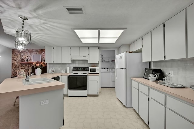 10412 Ireland St, Spring Hill, FL 34608 - kitchen with white appliances, a sink, visible vents, a peninsula, and washing machine and dryer