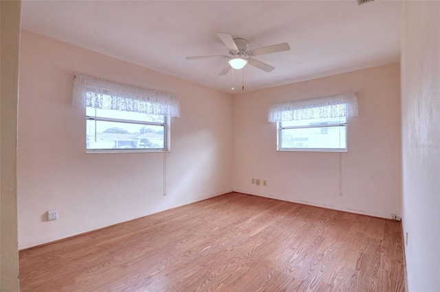 spare room with ceiling fan, a healthy amount of sunlight, and light wood-type flooring