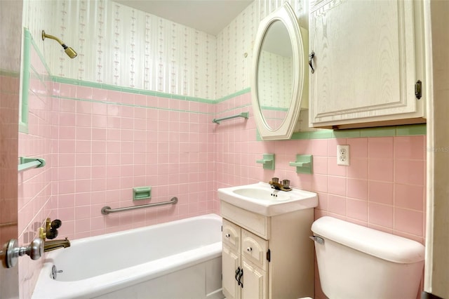 full bathroom with tile walls, vanity, tiled shower / bath combo, and toilet