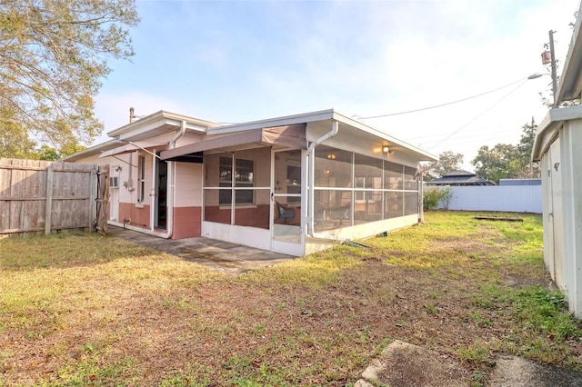 back of property featuring a yard and a sunroom