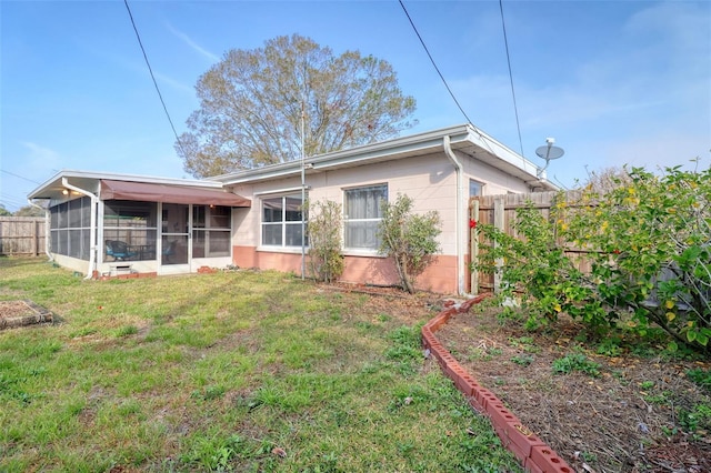 back of house with a lawn and a sunroom