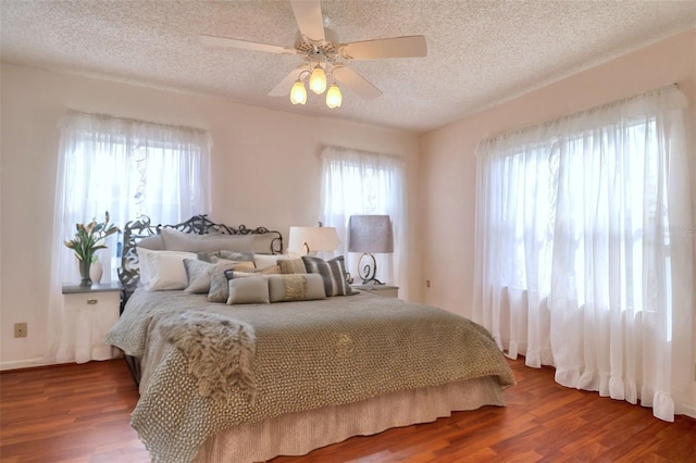 bedroom featuring ceiling fan, wood-type flooring, and a textured ceiling