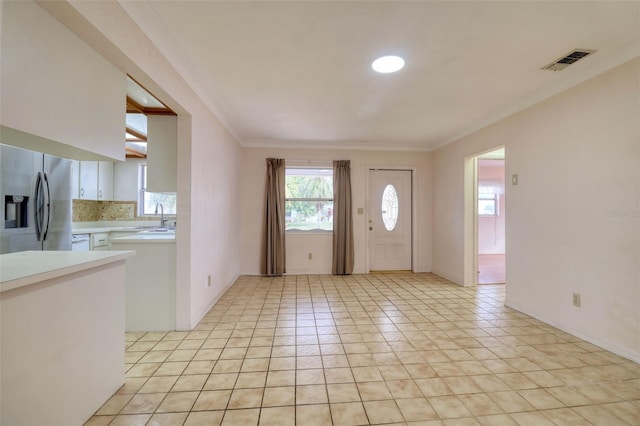 entryway featuring sink, light tile patterned floors, and ornamental molding