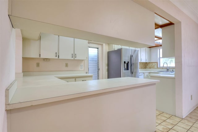 kitchen with white cabinets, sink, stainless steel fridge, and kitchen peninsula