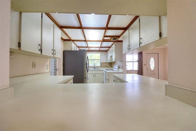 kitchen featuring sink, stainless steel refrigerator, white range with electric stovetop, decorative backsplash, and white cabinets