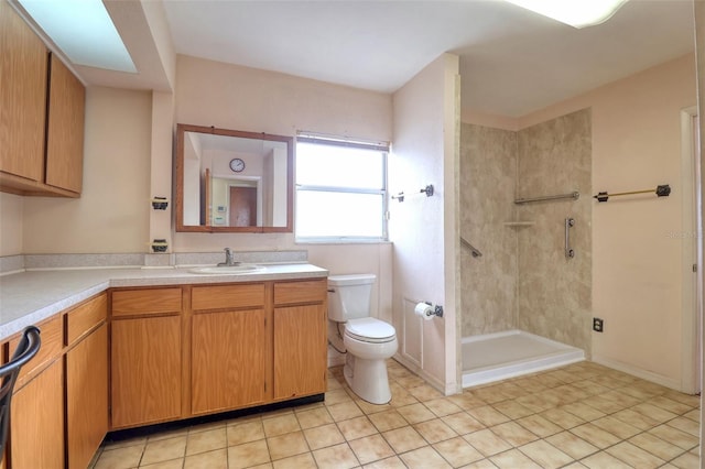 bathroom with tile patterned flooring, vanity, a tile shower, and toilet