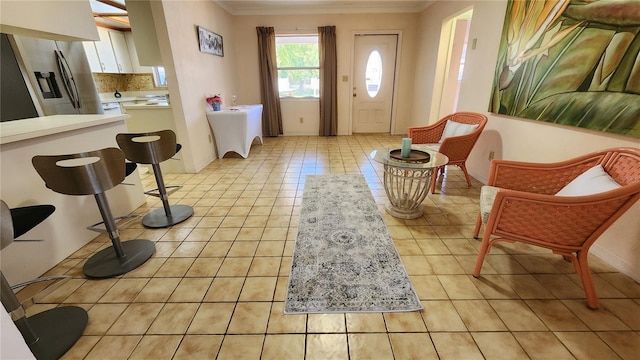 entrance foyer with baseboards, light tile patterned flooring, and crown molding