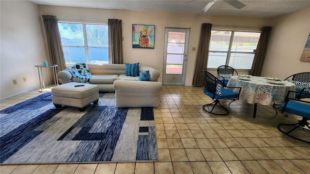 living room featuring a textured ceiling, ceiling fan, tile patterned floors, and a healthy amount of sunlight