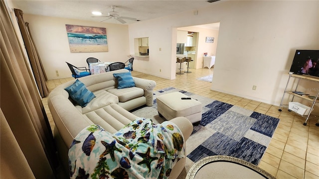 living area featuring tile patterned flooring, a ceiling fan, and baseboards