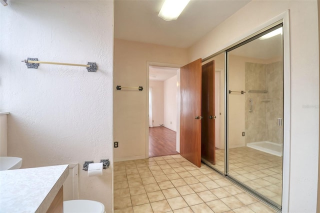 bathroom featuring toilet, a stall shower, tile patterned floors, and vanity