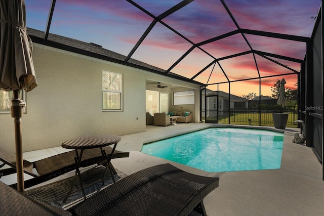 pool at dusk with an outdoor hangout area, glass enclosure, ceiling fan, and a patio area